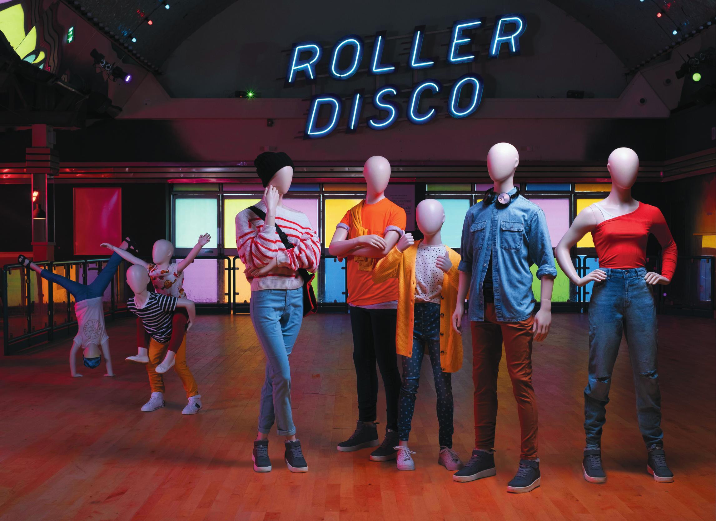 Mannequin by HOL A group of faceless mannequins, dressed in casual and colorful clothing from Our Collections, stands in various poses on a roller disco rink. The neon sign above them reads "ROLLER DISCO." The background includes roller disco elements and mood lighting for a vibrant atmosphere.