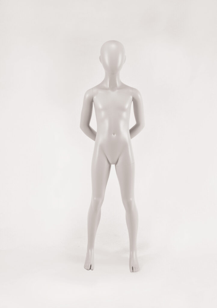 Mannequin by HOL A gray, featureless, child-sized mannequin stands upright. The mannequin has a smooth, expressionless face, and its arms rest by its sides. The background is a plain, light-colored surface, emphasizing the simple, modern design of this Farringdon Kids FK13 model.