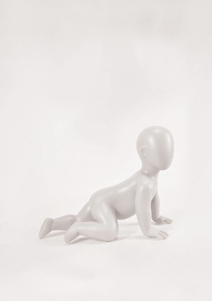 Mannequin by HOL A minimalist, faceless sculpture of a crawling baby is showcased against a light, neutral background. The statue has smooth, featureless surfaces and is depicted in a crawling position with both hands and knees on the ground, embodying the spirit of Farringdon Kids' playful essence.