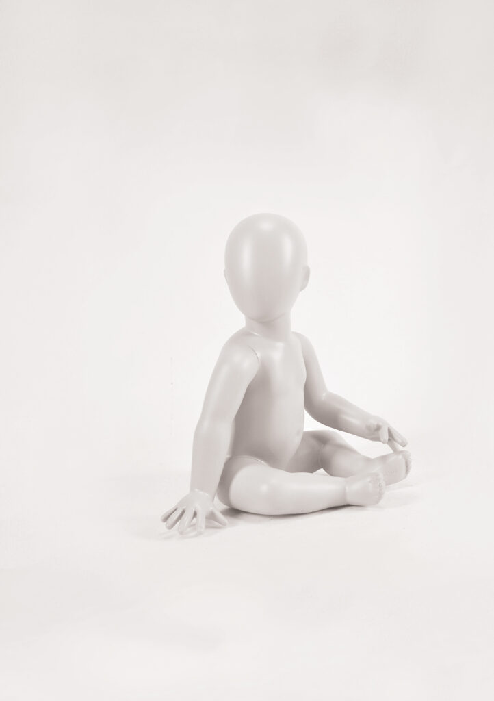 Mannequin by HOL A plain, featureless, light grey mannequin in a seated position on a white background. The figure's limbs are proportionate, and its head is smooth and oval without any facial features. This FK16 model captures the simplicity perfect for Farringdon Kids' minimalist displays.