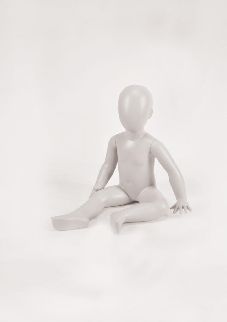Mannequin by HOL A plain, featureless, light-grey mannequin of a seated child from the Farringdon Kids collection. The FK18 mannequin has a smooth, rounded head without facial features and is positioned with its right leg extended and left leg bent. The background is white and uncluttered.